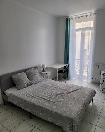 a bedroom with a bed and a desk and a window at le T3 à 600mètre du vieux port proche de la gare in Marseille