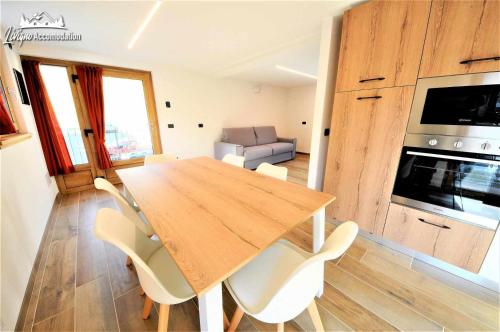 a kitchen with a wooden table and white chairs at Chalet Rin Patrizia Nuovo e vicino al centro in Livigno