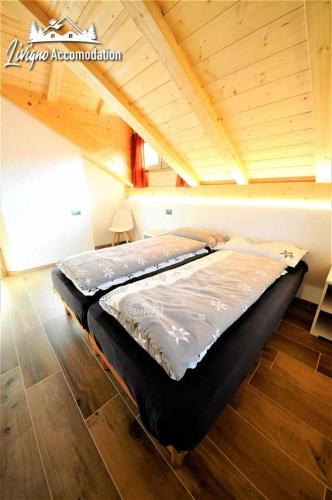 a large bed in a room with a wooden ceiling at Chalet Rin Patrizia by Livigno Accomodation in Livigno