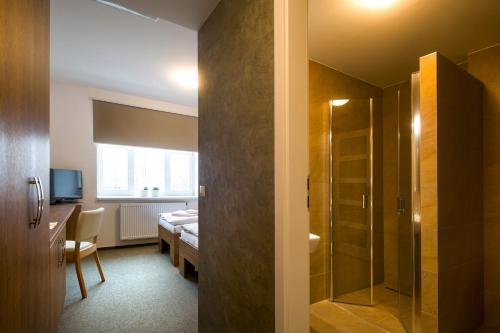 a room with a bathroom with a shower and a bedroom at Penzion Panský dvůr Telč in Telč