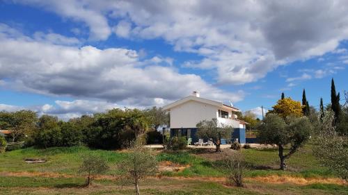 a white house in a field with trees at Vila Valmonte in Monte da Pedra Alva