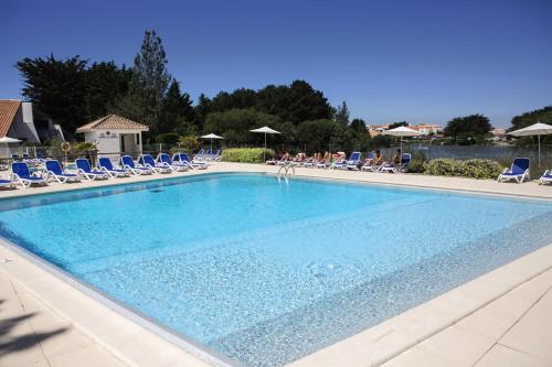 une grande piscine avec des chaises et des personnes dans l'eau dans l'établissement Belambra Clubs Saint-Jean-de-Monts - Les Grands Espaces, à Saint-Jean-de-Monts