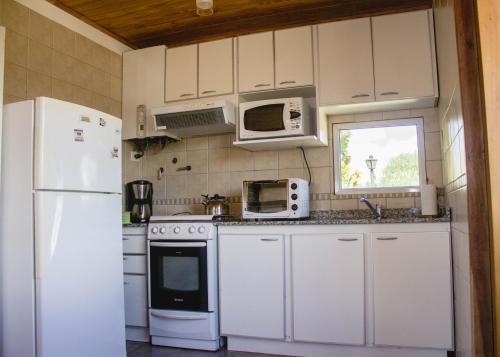 a kitchen with white appliances and a white refrigerator at Cabañas Rincones del Sur in Trevelin