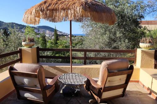 a patio with two chairs and a table with an umbrella at Olive Yard House in Skopelos Town