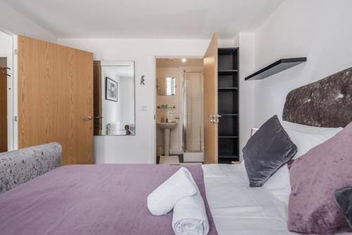 a bedroom with a bed with purple sheets and pillows at Beautiful 3-Bed Apartment in Romford in Romford