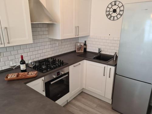 a kitchen with white cabinets and a stove and a sink at Explore the Croatian Coast and Relax in Modern Comfort in Kaštela