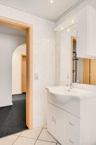 a white bathroom with a sink and a mirror at Gästehaus u Ferienwohnungen Veronika incl KönigsCard mit 200 kostenlosen Attraktionen in Unterammergau