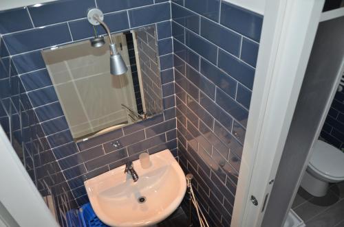 La salle de bains est pourvue de carrelage bleu, d'un lavabo et d'un miroir. dans l'établissement Un Caffè sul Balcone 2, à Rome