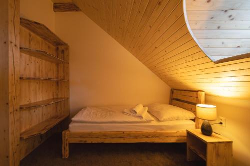 a bed in a room with a wooden ceiling at Bezručova škola in Staré Hamry