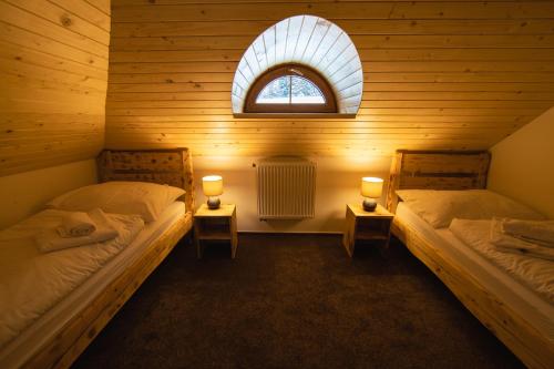 two beds in a wooden room with a window at Bezručova škola in Staré Hamry