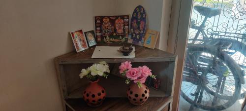 two vases with flowers in them on a shelf at Daya Dharmam Residency in Tiruvannāmalai