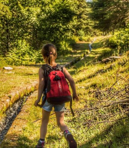 a little girl with a red backpack walking down a trail at Casas do Paço - Casas de Férias in Cabeceiras de Basto