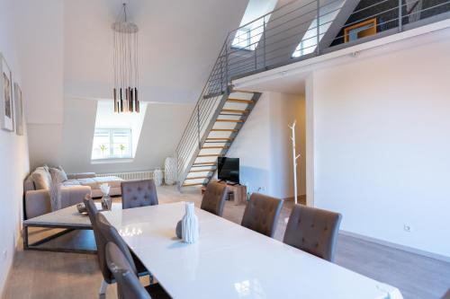 a dining room with a table and chairs and a staircase at La Fleur Appartement in Überlingen