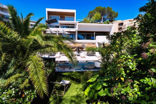 - un bâtiment avec une piscine et des palmiers dans l'établissement Villa Catleya Appart Hôtel, à Saint-Raphaël
