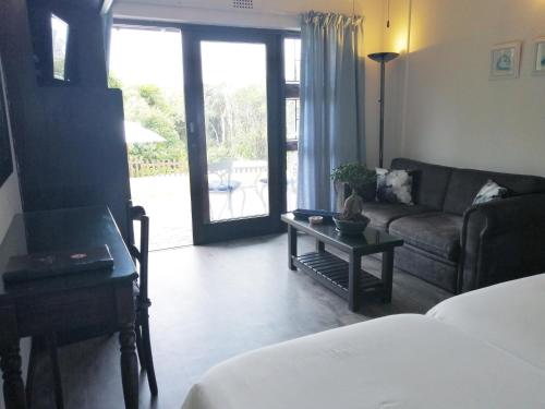 a bedroom with a living room with a couch and a table at Swallows Nest Plett in Plettenberg Bay