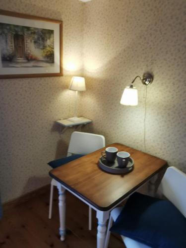 une table de salle à manger avec deux tasses et une lampe dans l'établissement La maison de Céline, à Arry