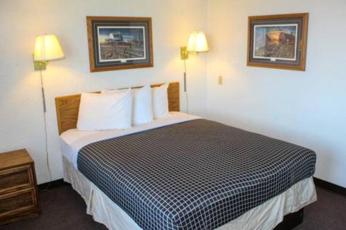 Camera d'albergo con letto, cuscini e 2 lampade. di Economy Hotel Minot a Minot