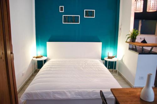 um quarto com uma cama branca e uma parede azul em Carducci green - Appartamento monolocale em Turim