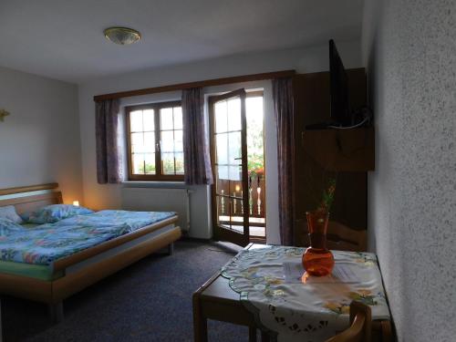 a bedroom with a bed and a table and windows at Pension und Bauernhof Petzold in Greiz