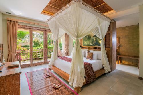 a bedroom with a canopy bed and a window at The Udaya Resorts and Spa in Ubud
