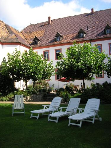 four white chairs sitting in the grass in front of a building at Schloss Triestewitz in Arzberg