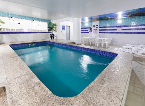 a pool with blue water in a room with white chairs at Centromar Hotel in Balneário Camboriú