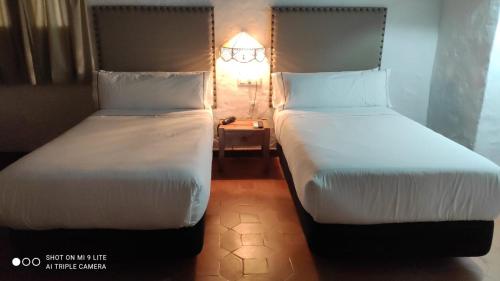 two beds sitting next to each other in a room at Hotel Tugasa Convento San Francisco in Vejer de la Frontera