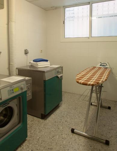 a laundry room with a washing machine and a stool at Residència Erasmus Gracia in Barcelona