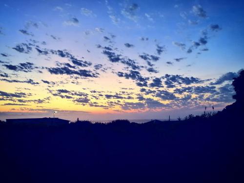 a cloudy sky at sunset with trees in the foreground at Swallows Nest Plett in Plettenberg Bay