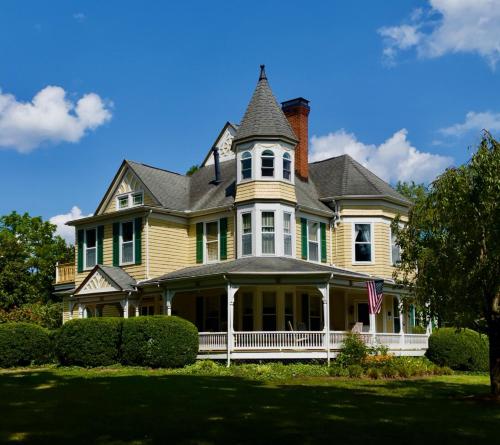 a large yellow house with a gambrel at The Oaks Victorian Inn in Christiansburg