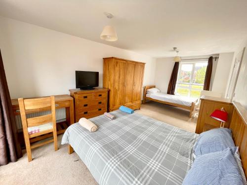 um quarto com uma cama e uma televisão numa cómoda em Basingstoke Townhouse Near Hospital em Basingstoke