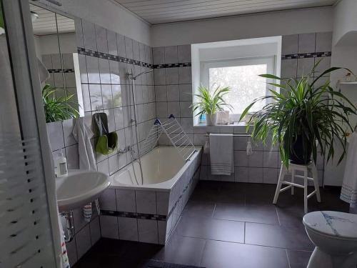 a bathroom with a tub and a sink and two plants at Apartment Dietze in Machern