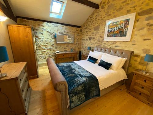 1 dormitorio con 1 cama en una habitación con paredes de piedra en La Porcherie en Saint-Mathieu
