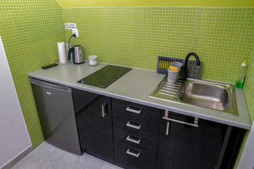 a small kitchen with a sink and green tiles at Noclegi Olszówka in Bukowina Tatrzańska