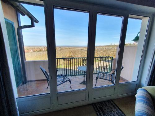 eine abgeschirmte Veranda mit einem Tisch und Stühlen auf dem Balkon in der Unterkunft Kanzel Residences in Beblenheim