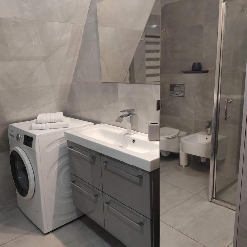 a bathroom with a washing machine and a sink at Gracja Dom przy Plaży in Rogowo
