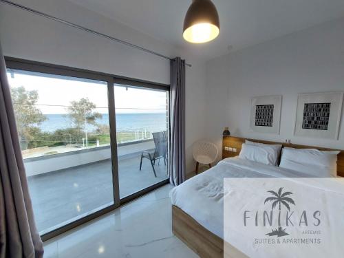 a bedroom with a bed and a view of the ocean at Finikas Suites & Apartments Airport By Airstay in Artemida