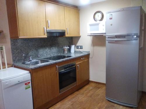 een keuken met houten kasten en een roestvrijstalen koelkast bij Apartamento con Piscina in Llança