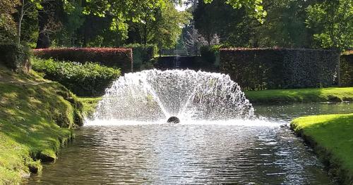 a fountain in a pond in a garden at LES 7 MEUSES - Restaurant & Hébergements HÔTELIERS - INSOLITES - WELLNESS - GÎTES in Profondeville