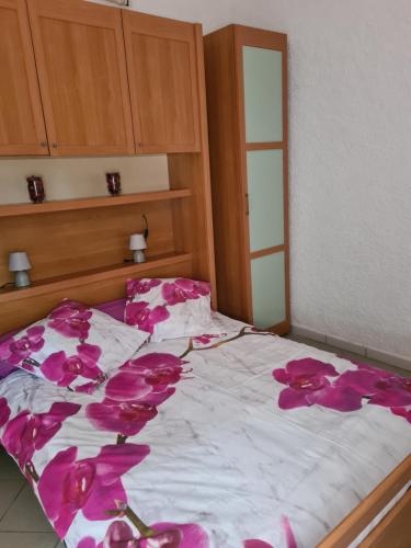 - un lit avec des fleurs roses dans une chambre dans l'établissement maisonnette à la campagne, à San-Gavino-di-Carbini
