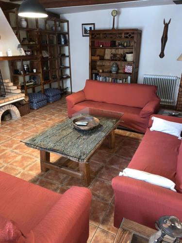 a living room with red couches and a coffee table at Casa rural Laguna Herrera in Campo de Cuéllar