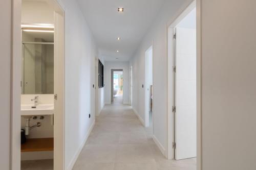 einen Flur in einem Haus mit weißen Wänden und einem Waschbecken in der Unterkunft Imagen Metrosol Deluxe by Valcambre in Sevilla