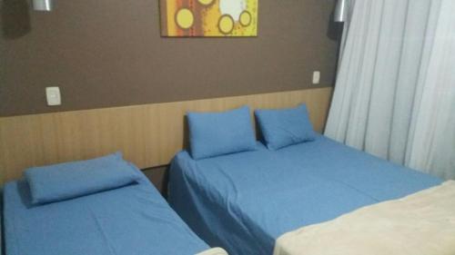 two beds with blue pillows in a bedroom at Parque Aldeia das Águas Flat in Barra do Piraí