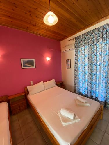 a bedroom with a white bed with a red wall at MARATHES STUDIOS in Agios Nikitas