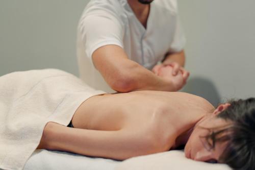 a woman laying on a bed next to a masseur at Hotel Villa Quiete in Montecassiano