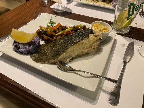 a plate of fish and vegetables on a table at Hôtel Restaurant l’Éolienne in Rouxmesnil-Bouteilles