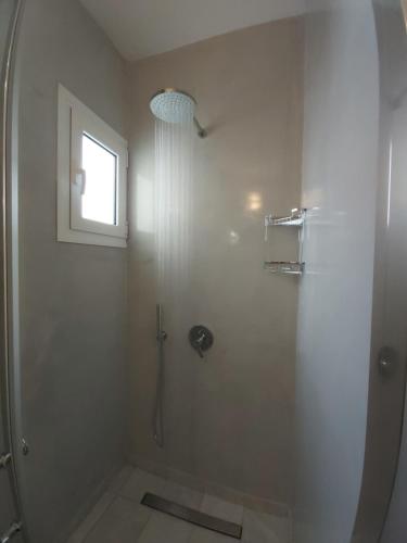 a bathroom with a shower with a window at Kiklamino Sunset Studios in Oia