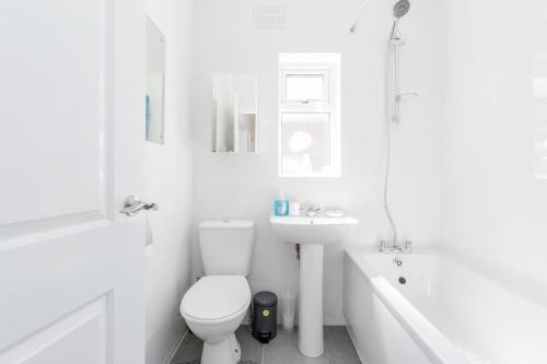 Charming 3-Bed Apartment in Romford في رومفورد: حمام أبيض مع مرحاض وحوض استحمام ومغسلة