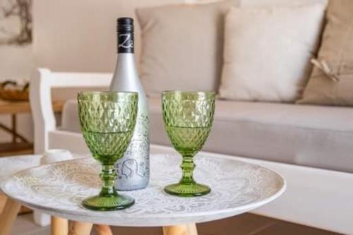 a bottle of wine and two green glasses on a table at Grannys Villas finiki in Karpathos Town