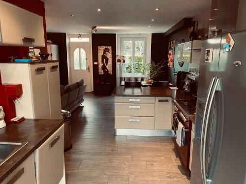 a kitchen with white cabinets and a refrigerator at Maison Auguste in Meyzieu